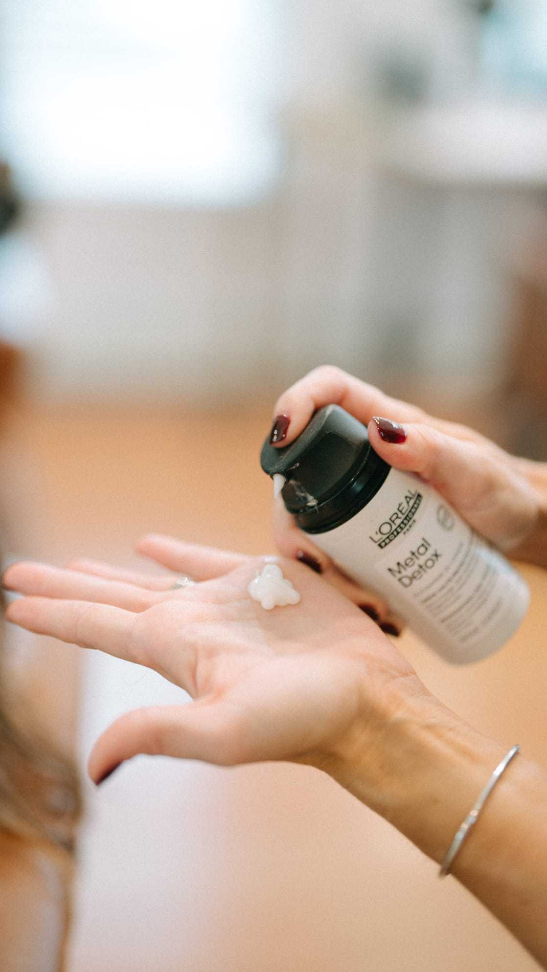 Applying L'Oréal Metal Detox shampoo to hands before hair treatment.