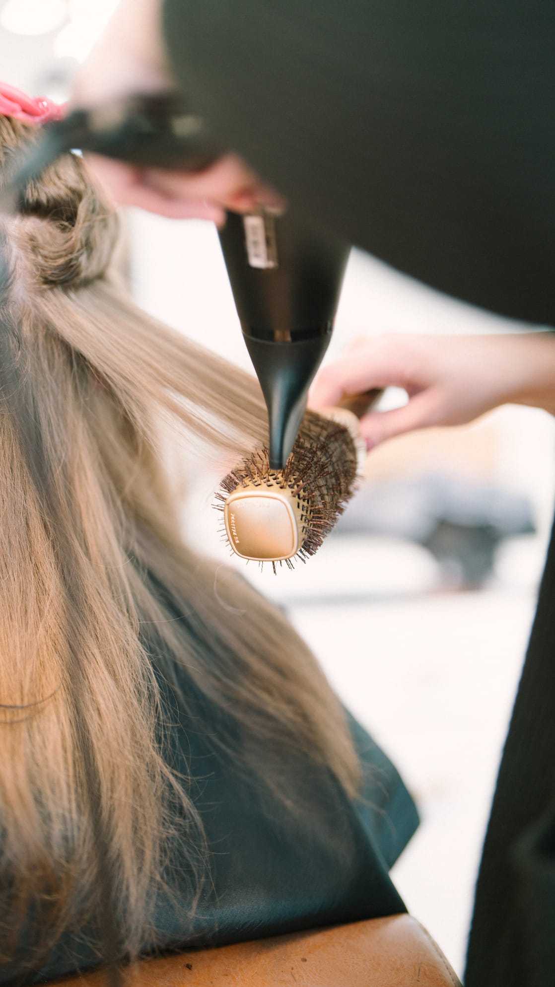 Blow-drying hair with a round brush at a salon.